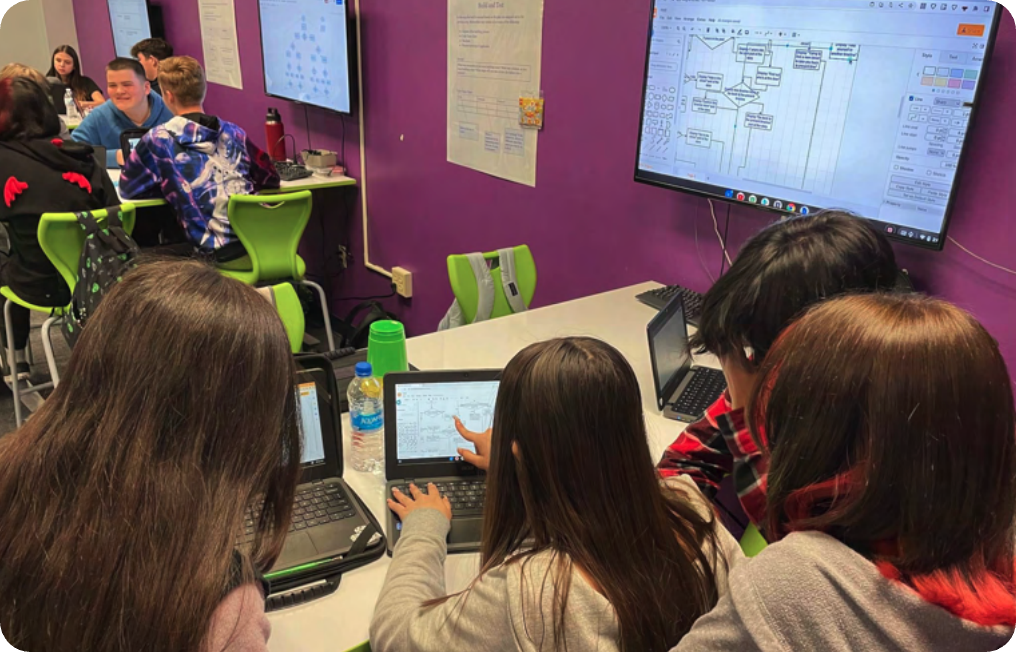 a group of people sitting at a table using laptops